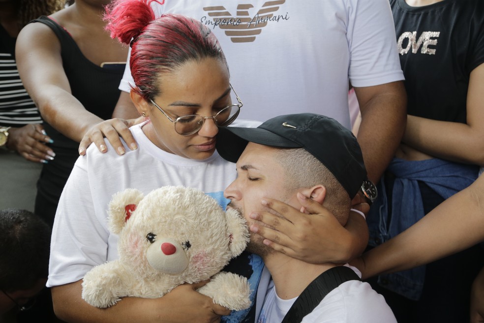 Thamires Assis e Dilson Moura, pais de Ester, se despendem da filha abraçados ao seu urso de pelúcia — Foto: Domingos Peixoto/Agência O Globo