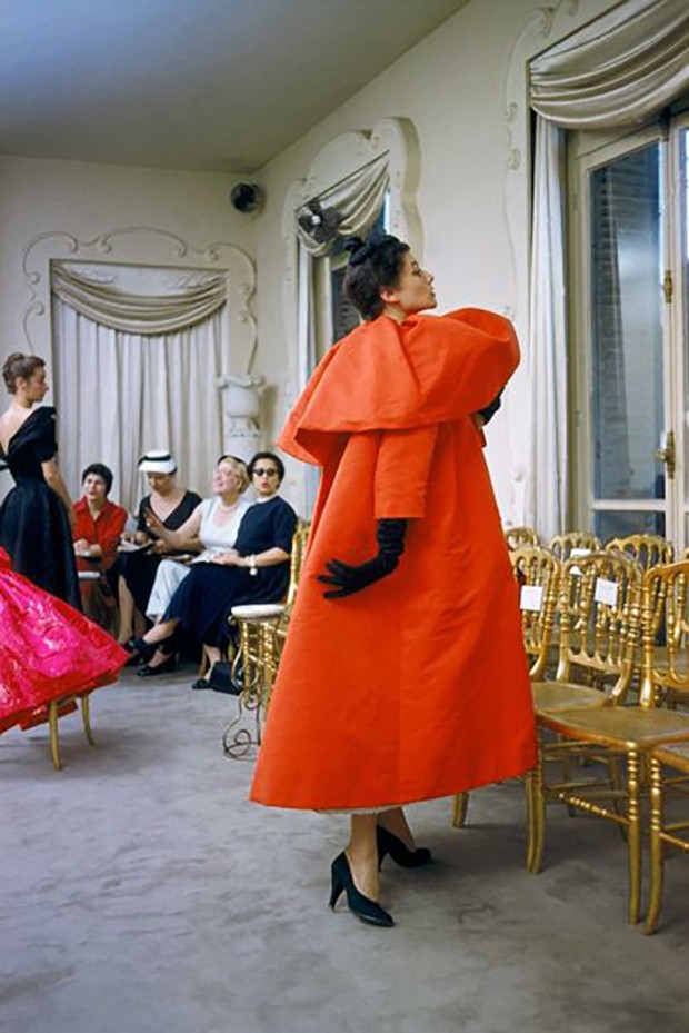 Model wearing a Balenciaga orange coat as buyers from US department store I. Magnin inspect a dinner outfit in the background. Paris, France, 1954 (Foto: © MARK SHAW, MPTVIMAGES.COM)