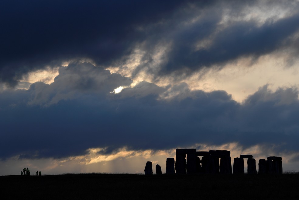 Agentes de segurança patrulham o perímetro do círculo de pedras de Stonehenge durante o por do sol, onde as celebrações oficiais do Solstício de Verão foram canceladas devido à propagação da doença por coronavírus (Covid-19), perto de Amesbury, na Grã-Bretanha, em junho de 2020 — Foto: Toby Melville/Reuters/Arquivo
