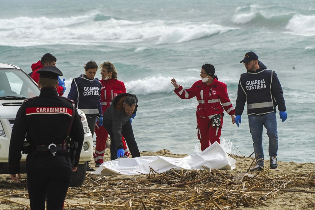 Voluntários da Cruz Vermelha ajudam na retirada de um corpo da praia no sul da Itália em 26 de fevereiro de 2023 — Foto: Antonino Durso/LaPresse via AP