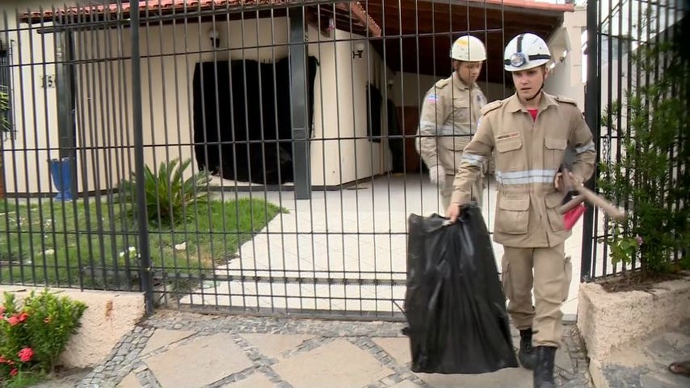 Bombeiros saem com sacos plásticos de casa onde crianças morreram em Linhares (Foto: Reprodução / TV Gazeta)
