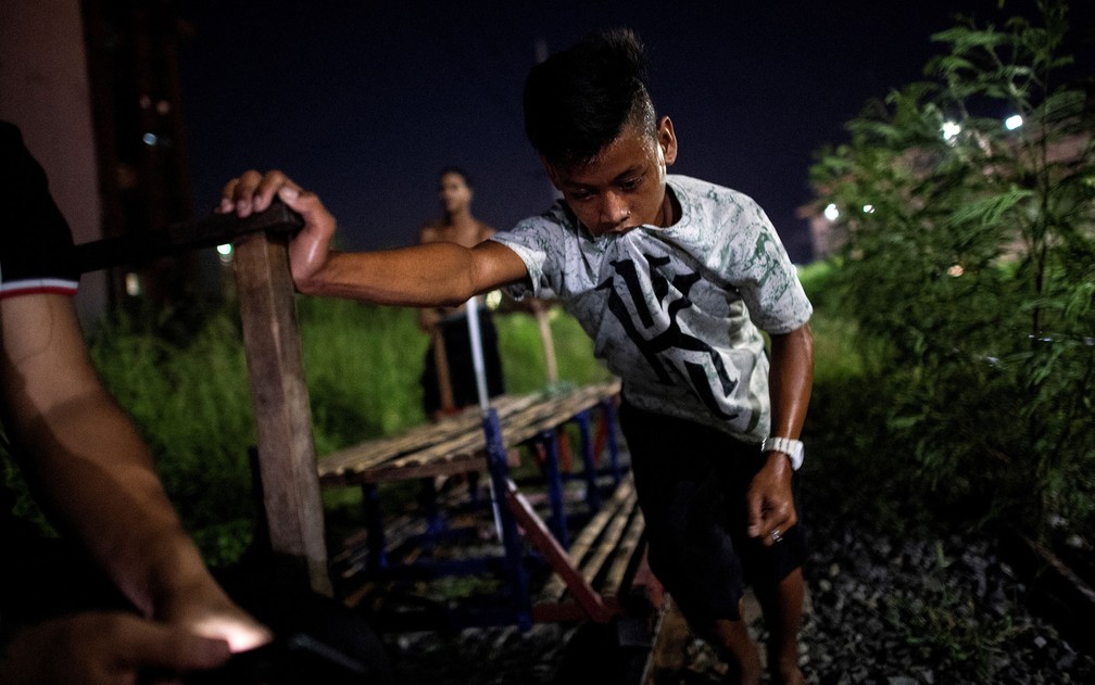 Foto de 19 de outubro mostra menino ajudando a empurrar carrinho de passageiros em linha de trem de Manila — Foto: Noel Celis/AFP