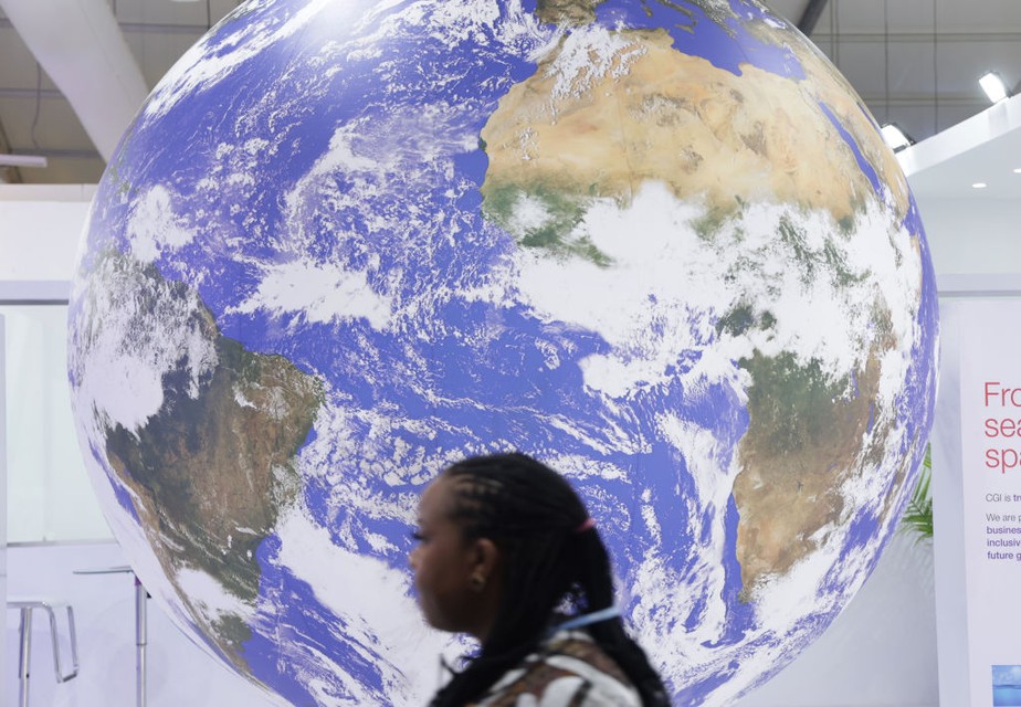 Uma participante da conferência passa por uma representação giratória do Planeta Terra durante a COP27.
