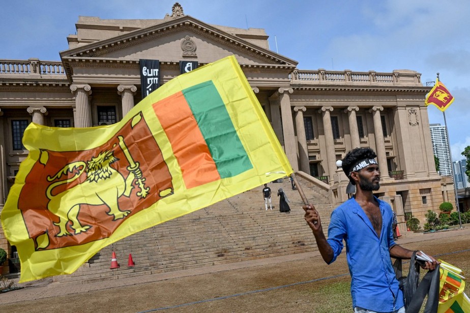 Um homem usa uma faixa na cabeça com um slogan contra o presidente interino do Sri Lanka, Ranil Wickremesinghe, enquanto agita a bandeira nacional do Sri Lanka perto do secretariado presidencial em Colombo