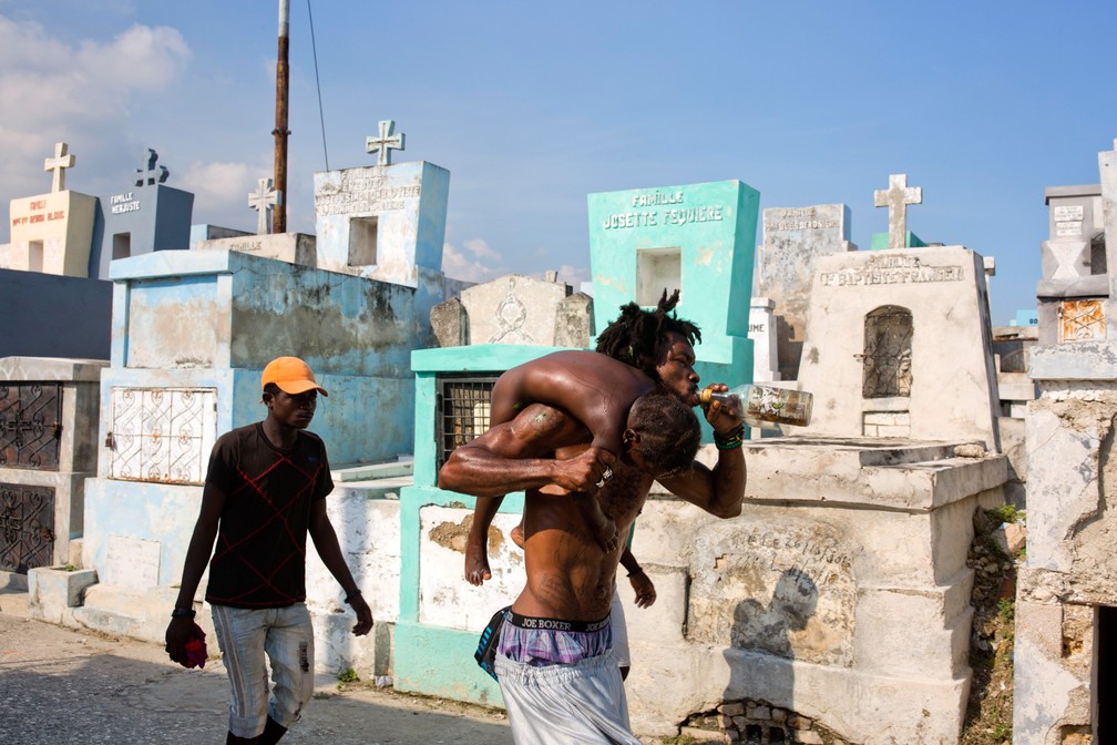 Um homem que supostamente está possuído pelo espírito de Gede cuida de uma menina doente durante o Festival anual de vodu de Fete Gede em Porto Príncipe, no Haiti, na sexta (1º) — Foto: Dieu Nalio Chery/AP
