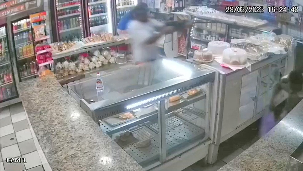 Homem de fuzil persegue alvo em padaria no Estácio — Foto: Reprodução/TV Globo