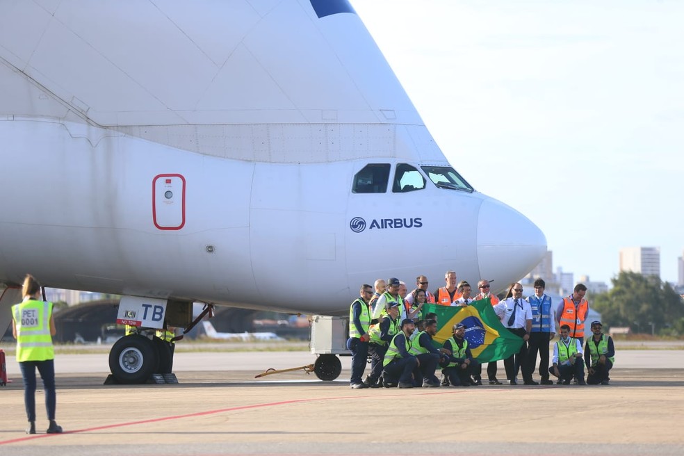 Equipe de pilotagem do avião beluga é recepcionada pelos funcionários do Aeroporto de Fortaleza com a bandeira do Brasil. — Foto: Fabiane de Paula/SVM