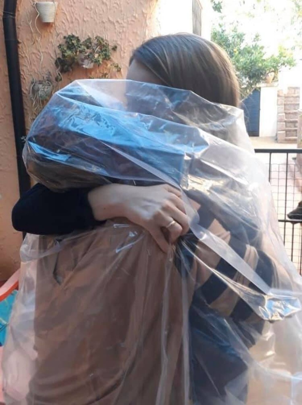 Mãe e filha se abraçaram protegidas por um plástico após 45 dias sem se ver — Foto: Andrea Fogaça Monteiro/Arquivo pessoal