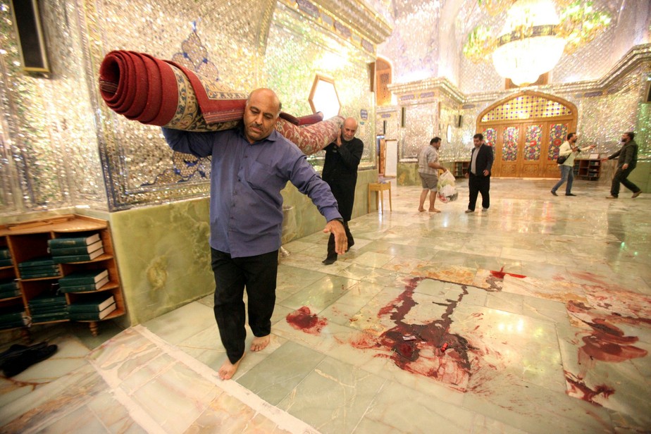 Trabalhadores limpam local após ataque armado no mausoléu Shah Cheragh na cidade iraniana de Shiraz
