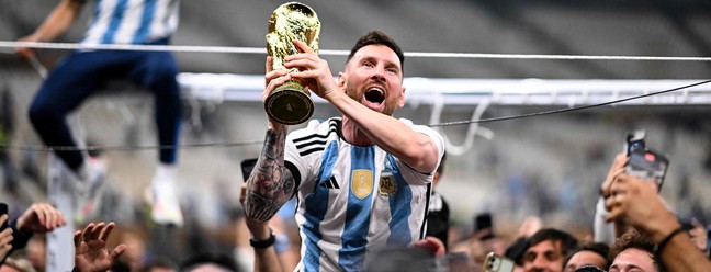 Lionel Messi carrega a taça e é carregado pela torcida argentina no Catar: herói nacional — Foto: Kirill Kudryavtsev
