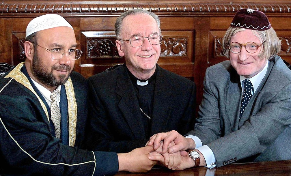 O líder muçulmano Armando Hussein Saleh, o arcebispo Claudio Hummes e o rabino Henry Sobel dão as mãos em coletiva de imprensa marcando a Celebração da Paz Mundial, em resposta aos ataques do 11 de Setembro, no dia 20 de setembro de 2001 — Foto: Mauricio Lima/AFP