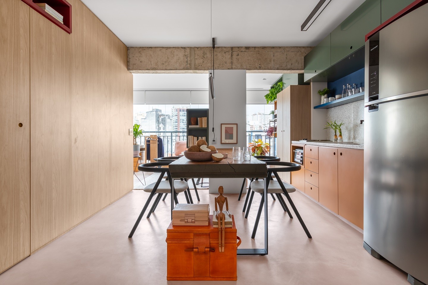 Cozinha em cimento queimado com mesa e cadeiras, geladeira e acessórios de cozinha.