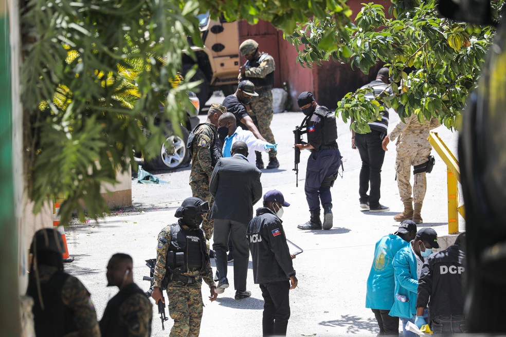Membros da polícia haitiana procuram evidências fora da residência presidencial em Porto Príncipe, em 7 de julho de 2021, onde o presidente do Haiti, Jovenel Moise, foi assassinado a tiros na madrugada — Foto: Valerie Baeriswyl/AFP 