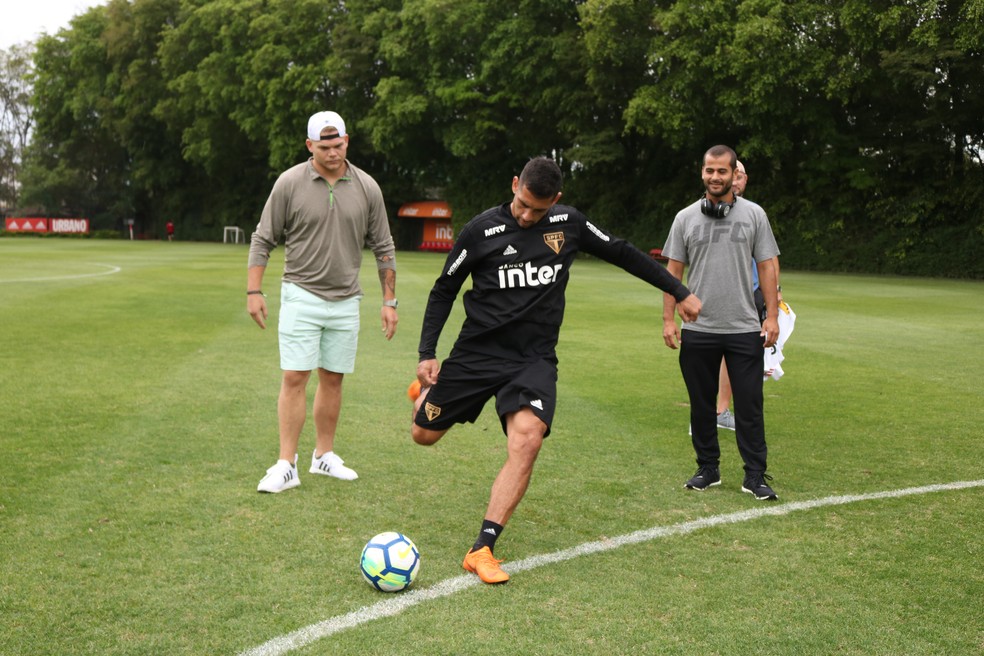 Diego Souza demonstra para Chase Sherman como chutar a bola, observado pelo amigo e treinador de jiu-jítsu Diego Moraes — Foto: Adriano Albuquerque