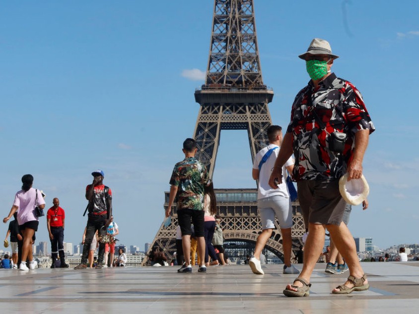 Turistas circulam de máscara próximo à Torre Eiffel, principal cartão postal de Paris, na França (Foto: Getty Images)