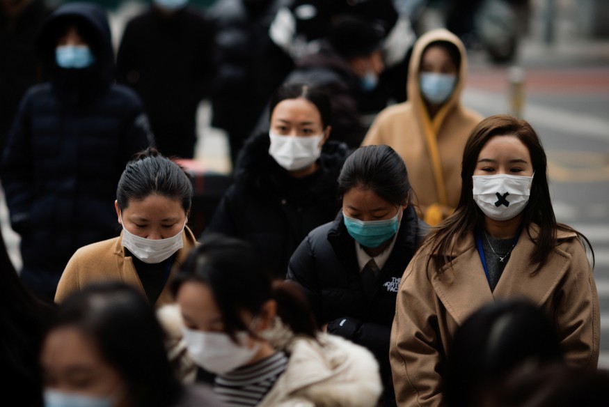 Chineses usam máscaras para atravessar a rua em Pequim