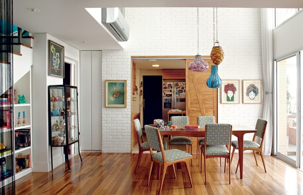 A sala de jantar tem mesa e cadeiras estilo anos 1950, garimpadas em feirinhas de antiguidades e forradas com tecido do Estúdio Zero, do Recife, e pendentes da Ethnix. Ao fundo, na parede de tijolos aparentes, a porta de correr que leva à cozinha (Foto: Victor Affaro)