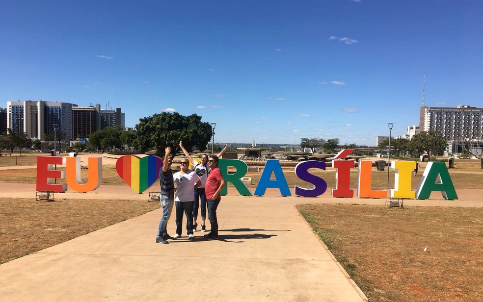 Turistas tiram foto em frente a escultura em homenagem a BrasÃ­lia com cores da bandeira LGBT (Foto: Luiza Garonce/G1)