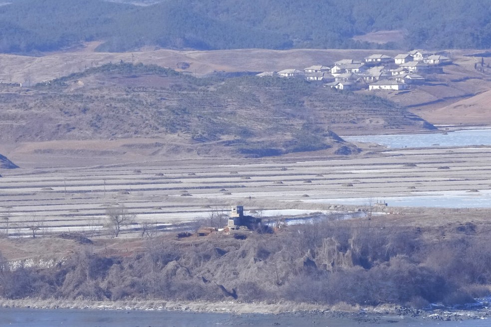 Povoado de Kaepoong, na Coreia do Norte, e plantação são vistas ao fundo, atrás de posto de controle na fronteira com a Coreia do Sul. — Foto: Ahn Young-joon/ AP 