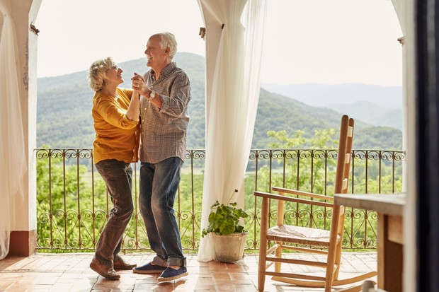 Loving senior couple dancing in balcony. Happy man and woman are spending leisure time together. They are at home. (Foto: Getty Images)