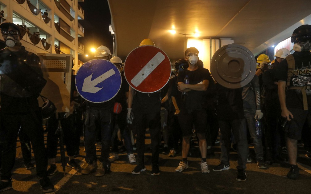 Manifestantes em Hong Kong se protegem com escudos feitos por placas de sinalização urbanas, cartazes com mensagens, e até skates — Foto: Vivek Prakash/AFP