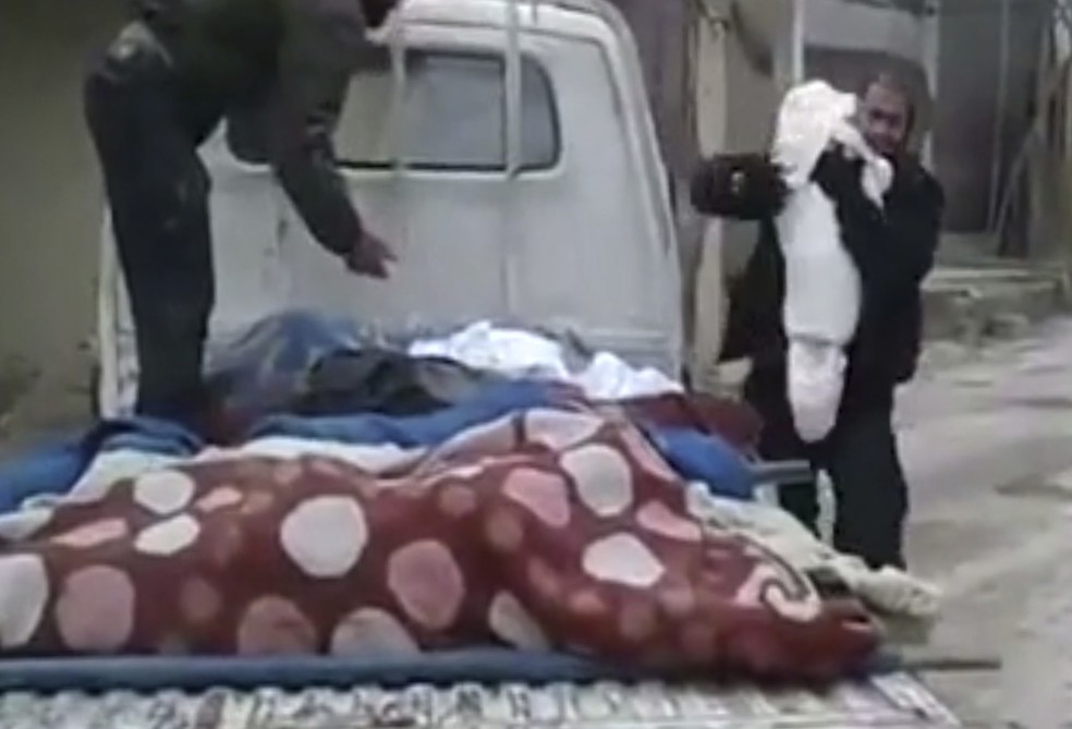 Imagem tirada de vídeo divulgado no dia 21 de fevereiro de 2018 pelo grupo sírio opositor Ghouta Media Center e autenticado pela Associated Press mostra homem (à dir.) abraçado ao corpo de seu filho morto durante bombardeios em Guta Oriental, perto de Damasco  (Foto: Ghouta Media Center via AP)