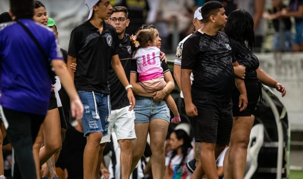Crian&ccedil;a sendo levada pela m&atilde;e ap&oacute;s confus&atilde;o na Arena Castel&atilde;o.  &mdash; Foto: Thiago Gadelha/Sistema Verdes Mares