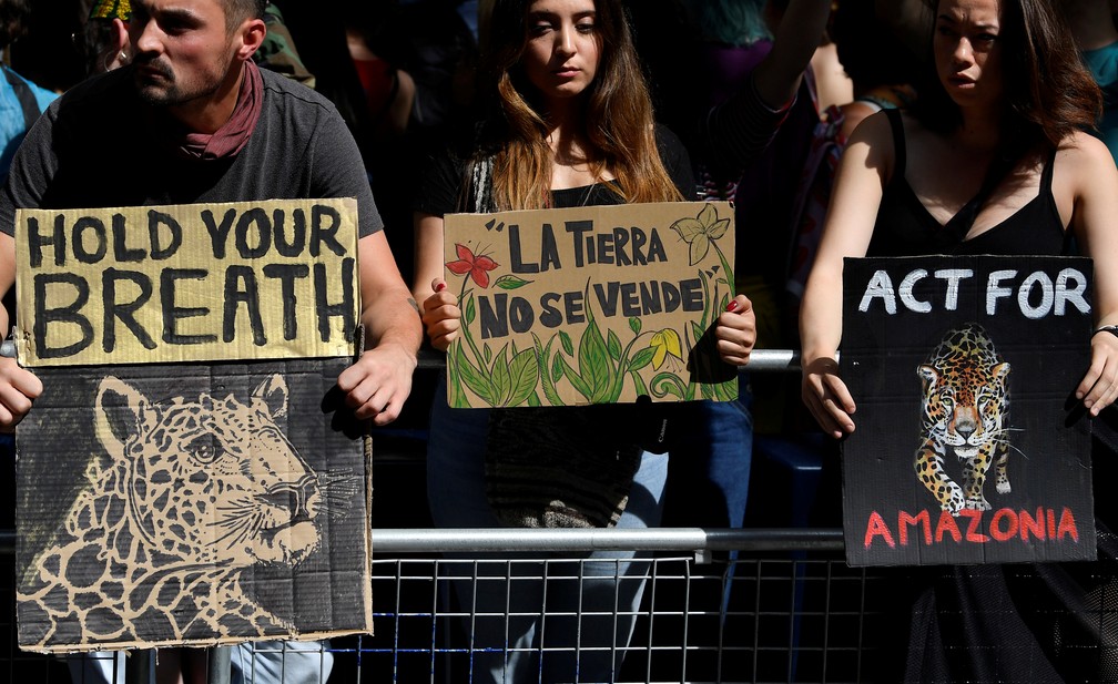 Manifestantes da Extinction Rebellion seguram placas com dizeres "segure a respiração", "a terra não se vende" e "ajam pela Amazônia" durante protesto em frente à embaixada brasileira em Londres nesta sexta-feira (23). — Foto: Toby Melville/Reuters