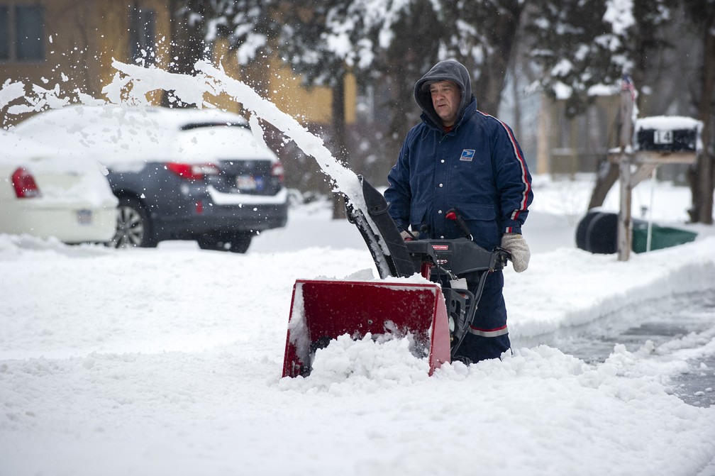 Funcionário dos correios tenta tirar neve da calçada em Saugus, Massachusetts. — Foto: Joseph PREZIOSO / AFP