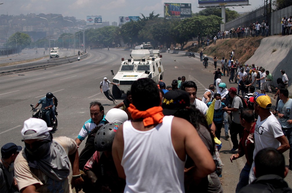 Manifestante oposicionista corre antes de ser atropelado por um veÃ­culo militar diante da base aÃ©rea 'La Carlota', em Caracas â€” Foto: Ueslei Marcelino/Reuters