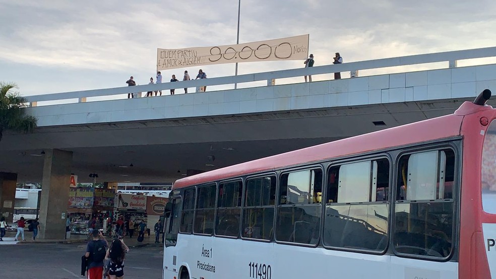 Artistas do DF estendem faixa no viaduto da Rodovirária de Brasília, para lembrar 30 mil mortos pela Covid-19  — Foto: Hugo Evaristo/TV Globo