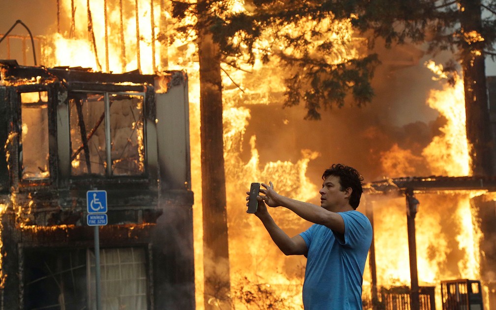 Rudy Habibe, de Porto Rico, fotografa o incêndio no Hilton Sonoma Wine Country hotel, onde estava hospedado, no domingo (8) (Foto: AP Photo/Jeff Chiu)