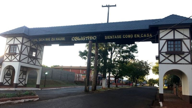 Uma saudação em alemão e espanhol recebe quem chega a Obligado, no sul do Paraguai (Foto: BBC News)