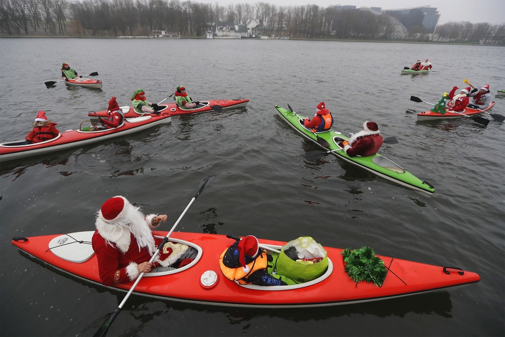 Papais noéis andam de caiaque no lago Komsomolskoye no sábado (14) durante corrida de temática natalina em Minsk, Belarus — Foto: Sergei Grits/AP