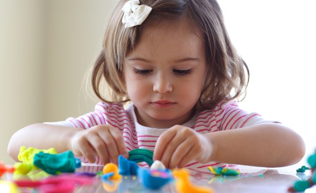 Criança brincando de massinha na mesa (Foto: Shutterstock)