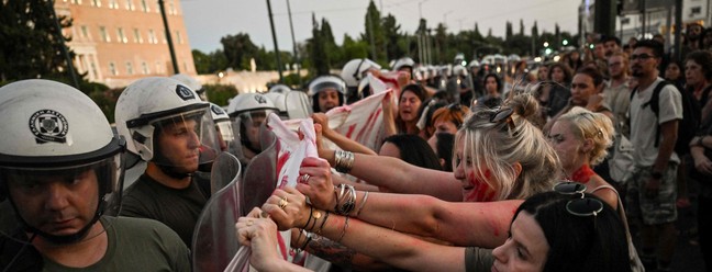 Mulheres entram em confronto com a polícia grega em frente ao parlamento, em Atenas, em protesto contra onda de feminicídio — Foto: LOUISA GOULIAMAKI / AFP
