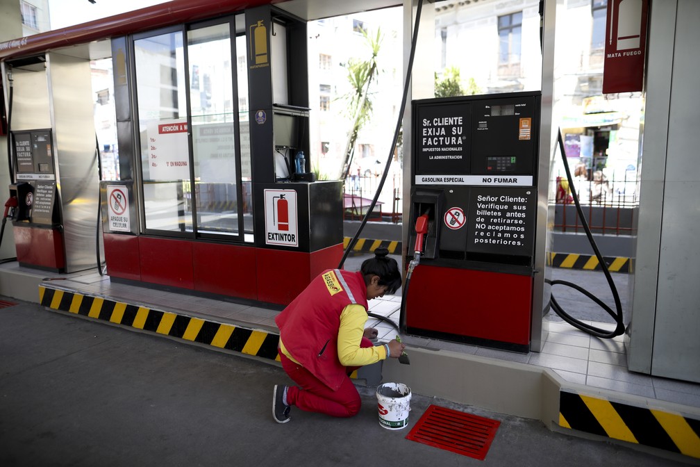 Funcionária de posto pinta o estabelecimento fechado em La Paz, na Bolívia, nesta segunda-feira (18) — Foto: Natacha Pisarenko/AP Photo