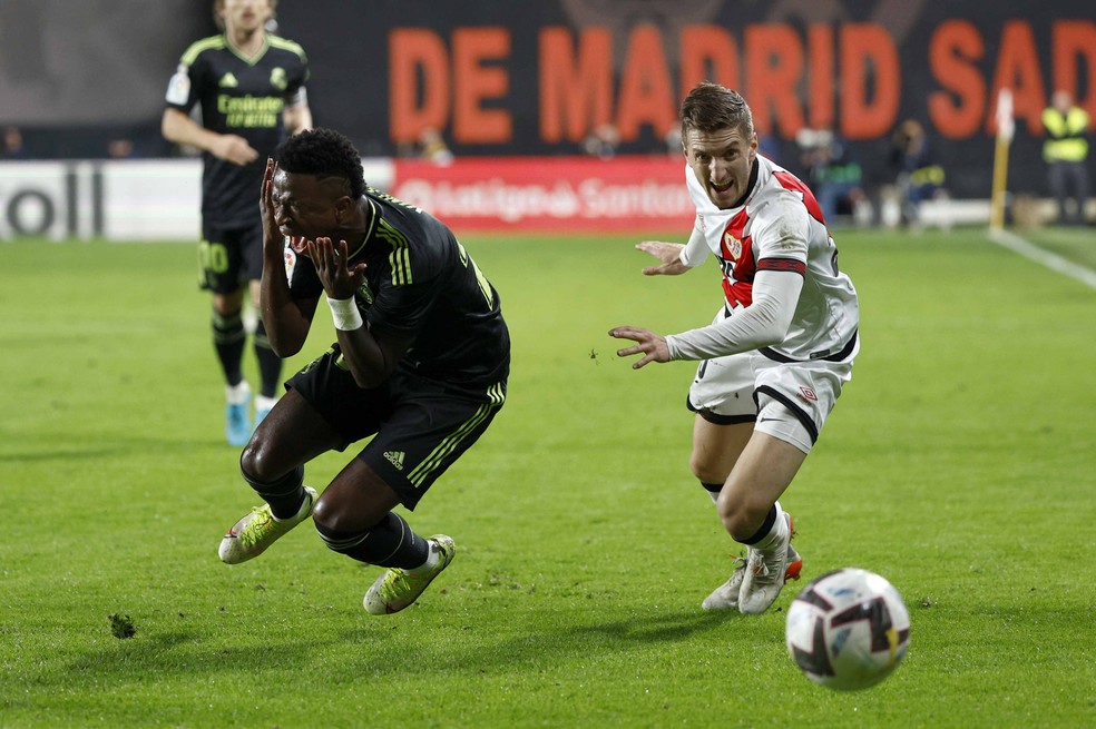 Vinicius Junior, do Real Madrid, sente dores no rosto ap&oacute;s ser atingido por Balliu, lateral do Rayo Vallecano &mdash; Foto: Rodrigo Jim&eacute;nez/EFE