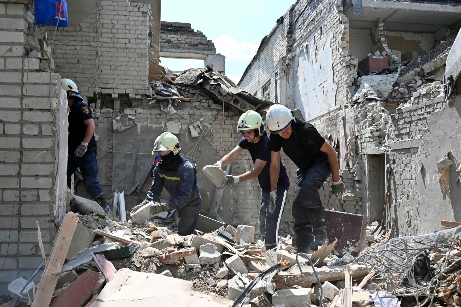 Equipes de resgate trabalham nas ruínas de um prédio escolar destruído por dois foguetes na cidade ucraniana de Kharkiv — Foto: SERGEY BOBOK / AFP
