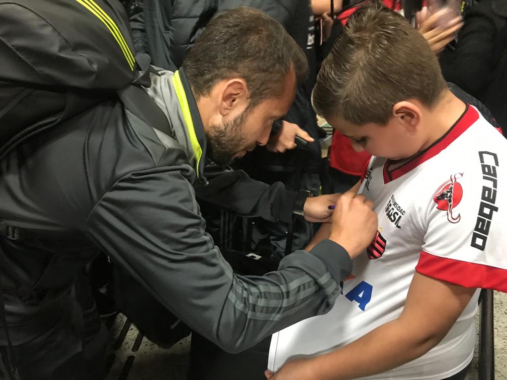 Everton Ribeiro dá autógrafo para um fã na chegada a Curitiba — Foto: Cahê Mota