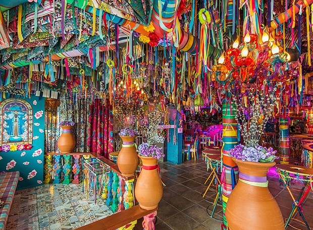 Fitas de todas as cores enfeitam o teto por completo, além de vasos com flores e pinturas nas paredes (Foto: Marcos Vollkopf/Divulgação)