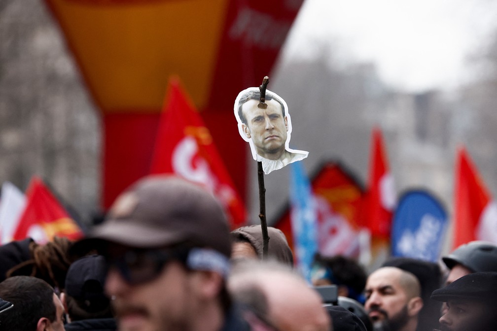 Um manifestante segura uma imagem que retrata o presidente francês, Emmanuel Macron, furado por uma vara, durante uma marcha contra o plano de reforma da previdência do governo em Paris, França, em 11 de março de 2023 — Foto: REUTERS/Benoit Tessier