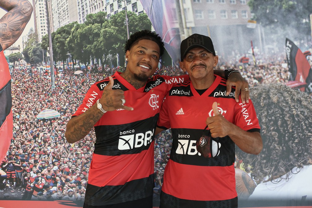 Marinho e o pai posam para foto em frente ao painel de festa da torcida — Foto: Gilvan de Souza/Flamengo