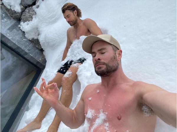 O ator Chris Hemsworth sem camisa, na companhia de um amigo, durante um banho de neve (Foto: Instagram)