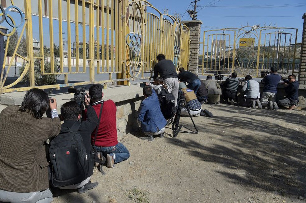 Jornalistas afegãos se concentram em frente ao canal de TV invadido por homens armados  (Foto: Shah Marai / AFP)