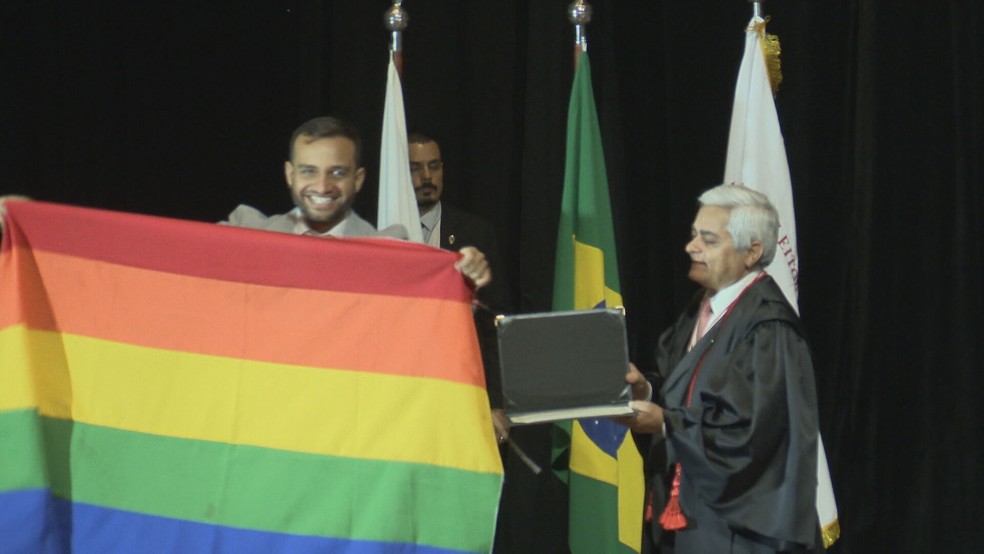 Deputado distrital Fábio Félix (PSOL) ergue bandeira LGBT ao ser diplomado, no DF — Foto: TV Globo/Reprodução