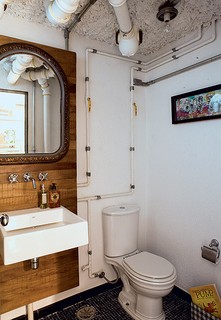 O lavabo da mesma casa também tem instalações expostas. Aqui, os canos estão totalmente aparentes