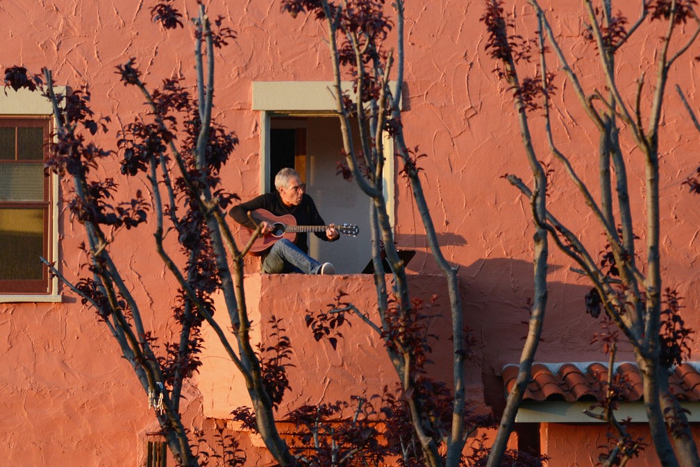 Danny Wertheimer toca violão e canta para os vizinhos de sua varanda em Oakland, na Califórnia, em 21 de março, dois dias após o governador da Califórnia implementar uma 'ordem de permanência em casa' em todo o estado — Foto:  Kate Munsch/Reuters