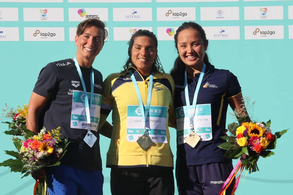 Ana Marcela Cunha no lugar mais alto do pÃ³dio em SetÃºbal, Portugal, cercada por Rachele Bruni e Samantha Arevalo â€” Foto: ReproduÃ§Ã£o / Facebook Fina