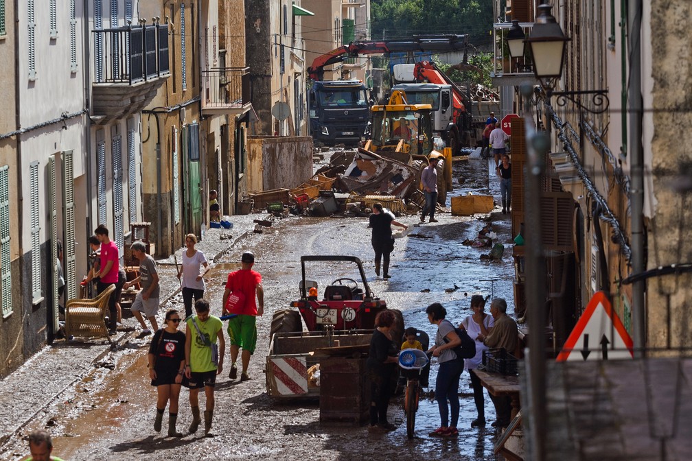 Moradores de Sant Llorenc, em Mallorca, ajudam nesta quinta-feira (11) a tirar escombros de rua inundada — Foto: Francisco Ubilla/AP Photo